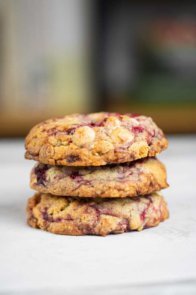 Cookie de framboesa com chocolate branco visto de lado mostrando bordas crocantes.