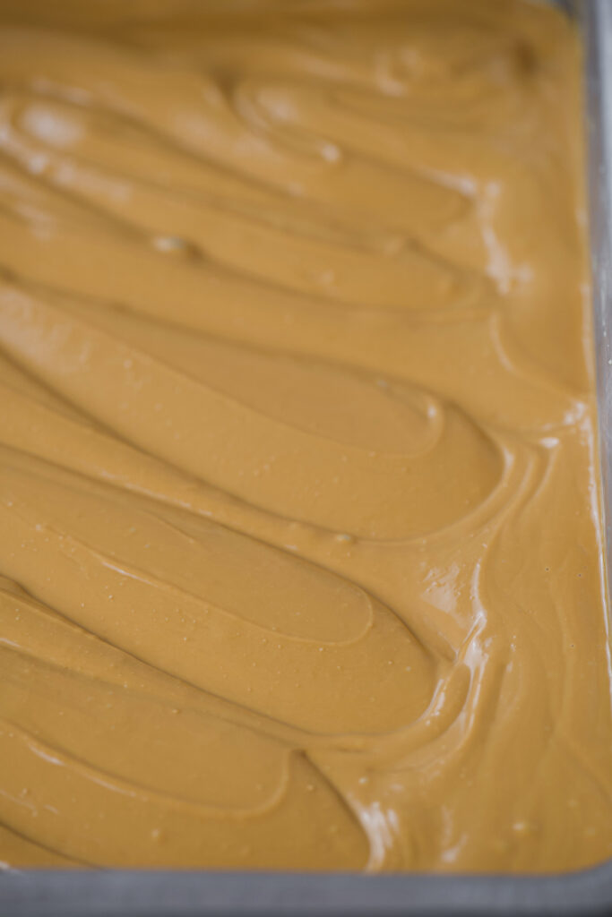 Chocolate branco caramelizado espalhado em uma assadeira, com textura cremosa e tom dourado uniforme, após 90 minutos de forno.