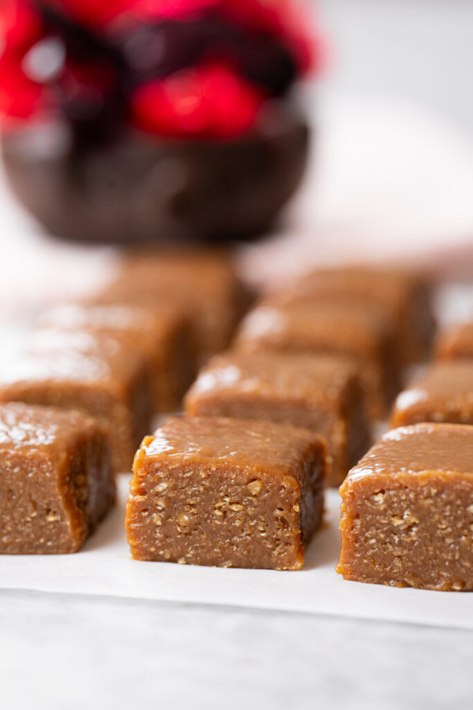 Close lateral de cocada fudge caramelizada com foco na textura do coco e brilho da superfície; fundo desfocado com clima junino.