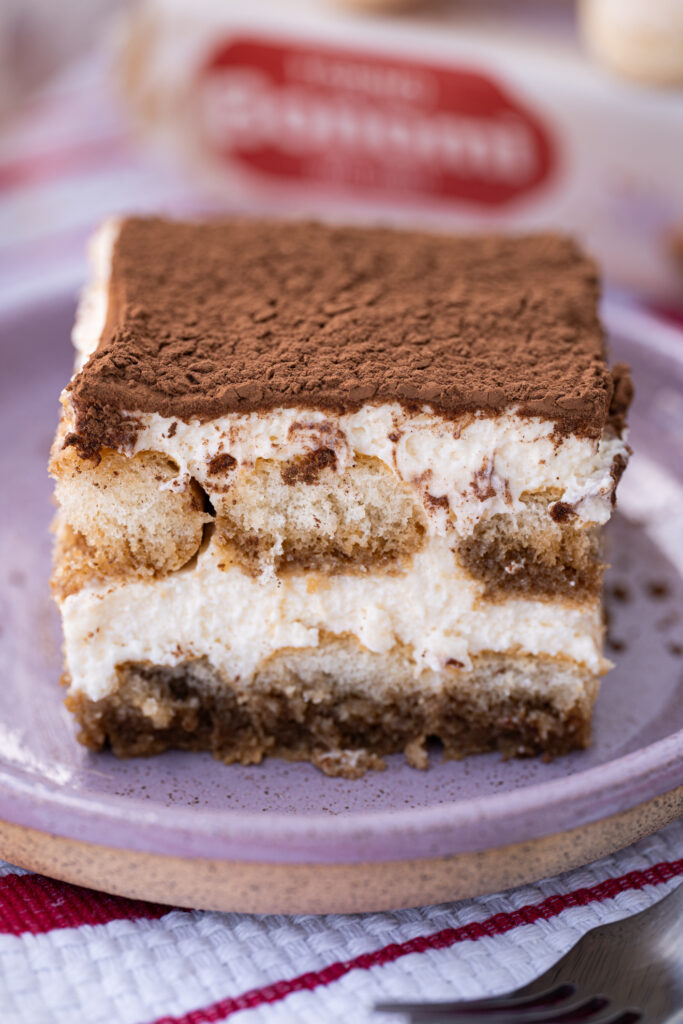 Close de tiramisu clássico mostrando as camadas de biscoito embebido no café e creme